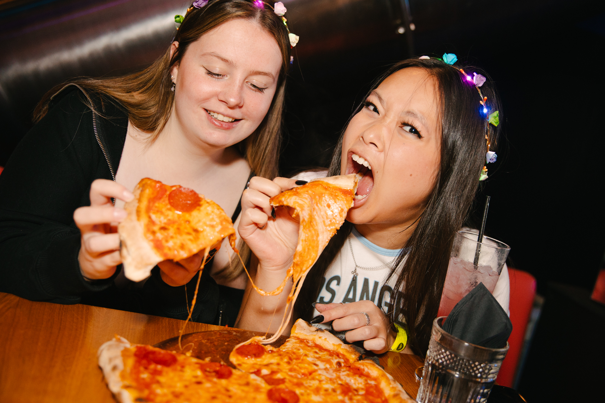 two girls eating pizza at a bottomless brunch