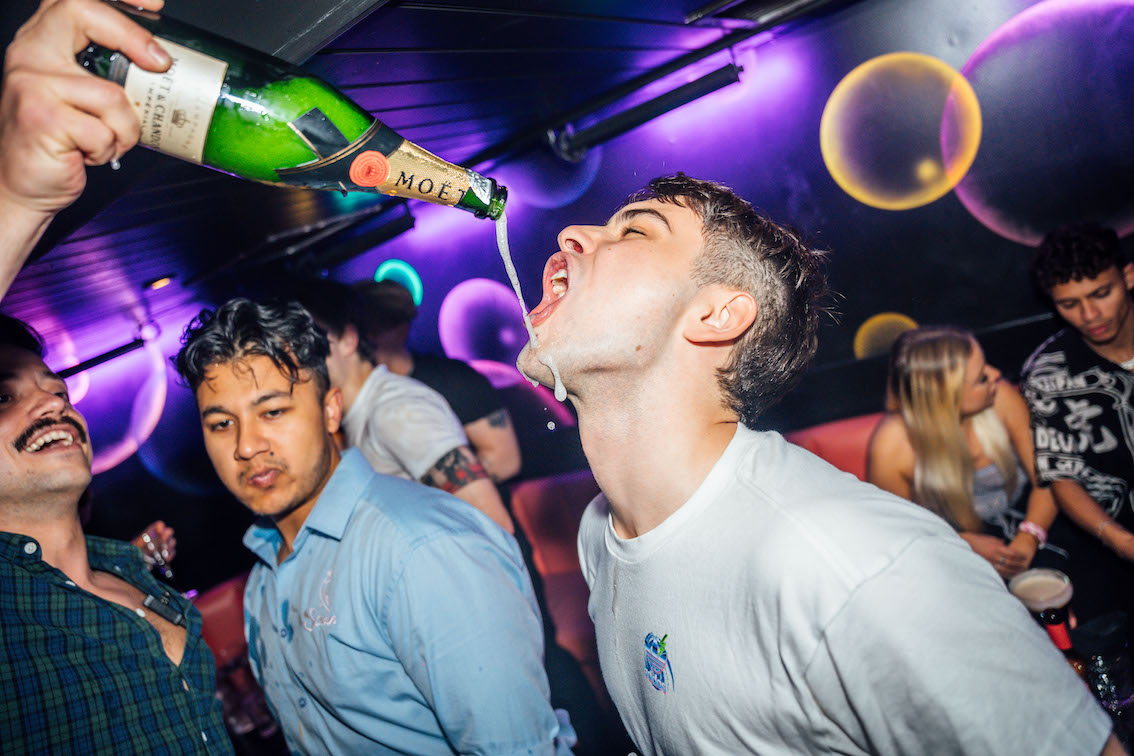 a man getting champagne poured into his mouth
