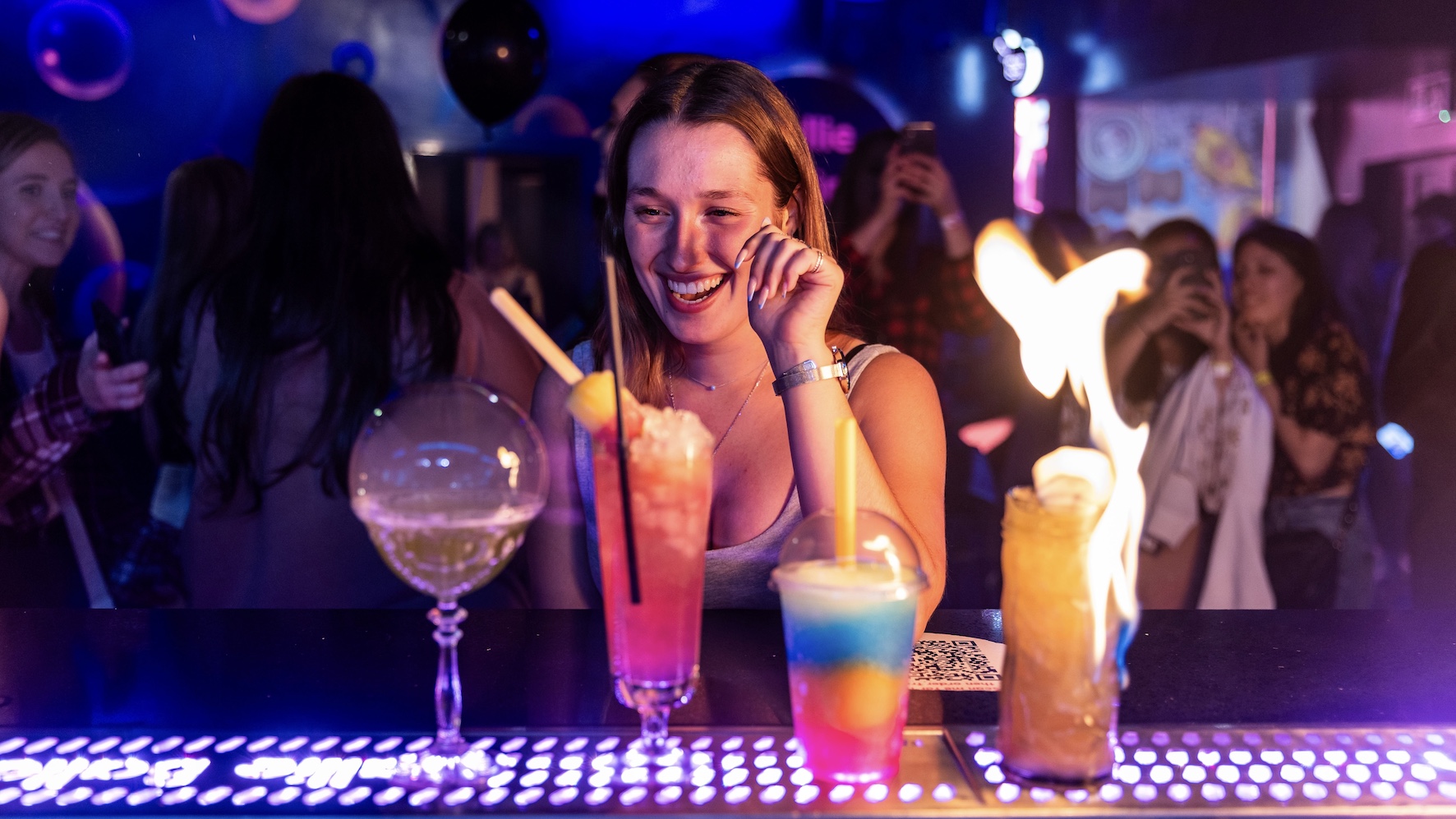 a girl admiring 4 different cocktails in front of her at the bar