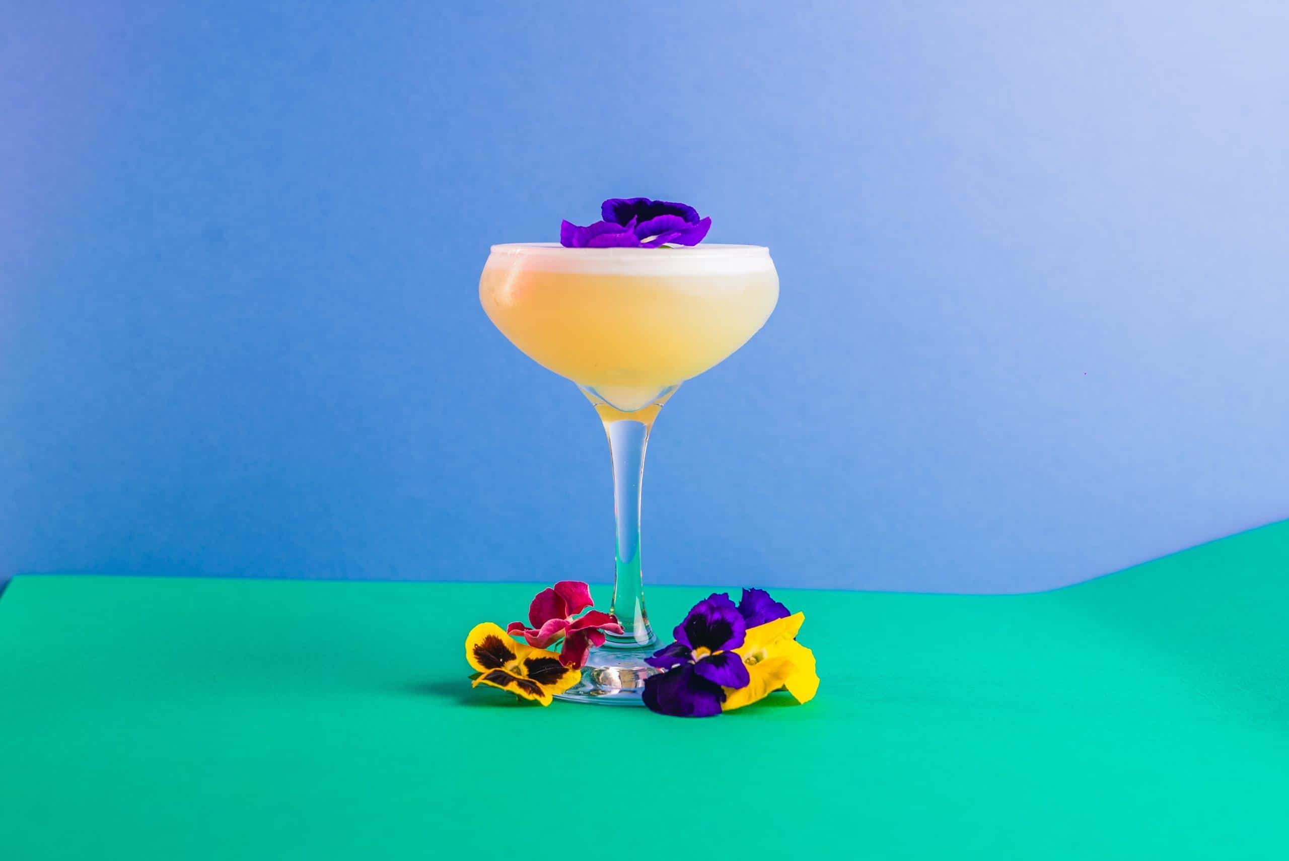 Vibrant cocktail in a martini glass with colorful flower garnishes, representing fun and lively nightlife at Ballie Ballerson.