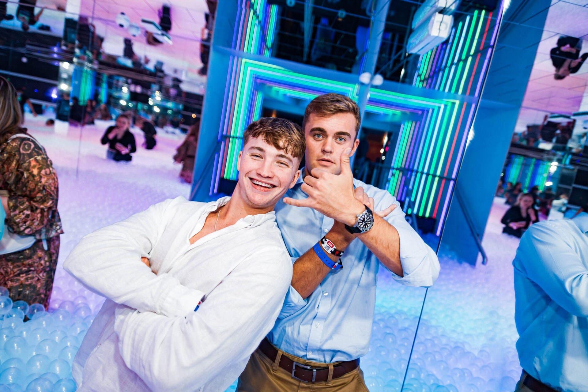 Man in blue shirt in rainbow ball pit throwing balls up