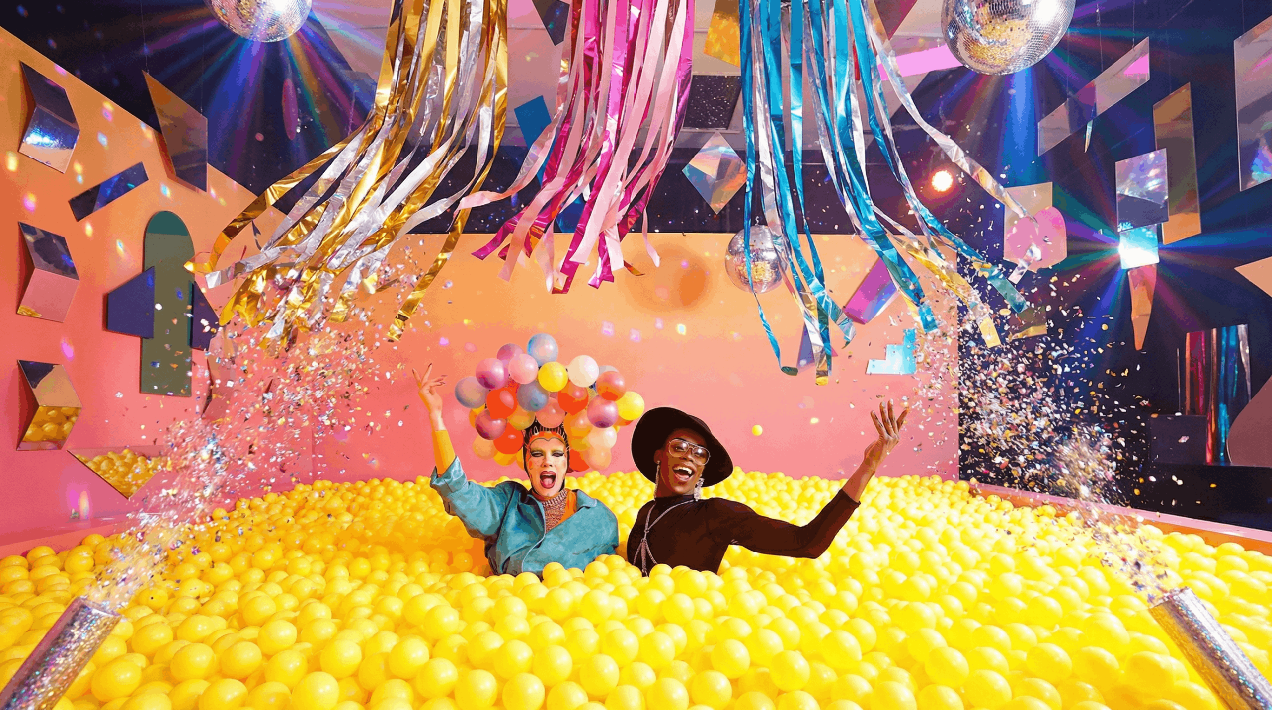 Vibrant drag queen celebration with colourful balloons and graffiti background at Sisterhood Bottomless Drag DJ Party.