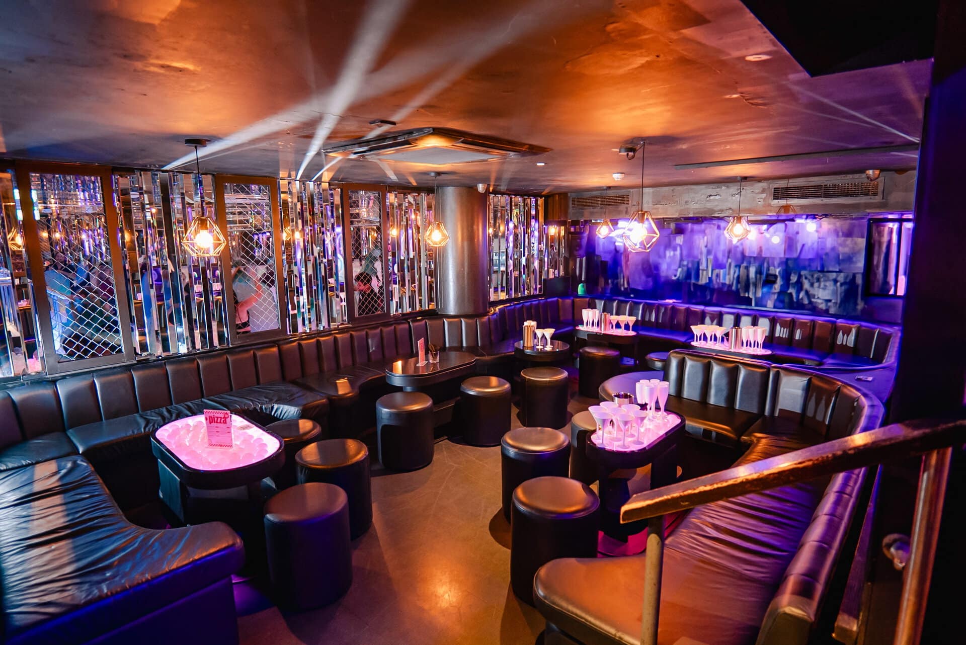 Vibrant indoor bar with red seating, colourful paper lanterns, and lush green plants at Ballie Ballerson London.